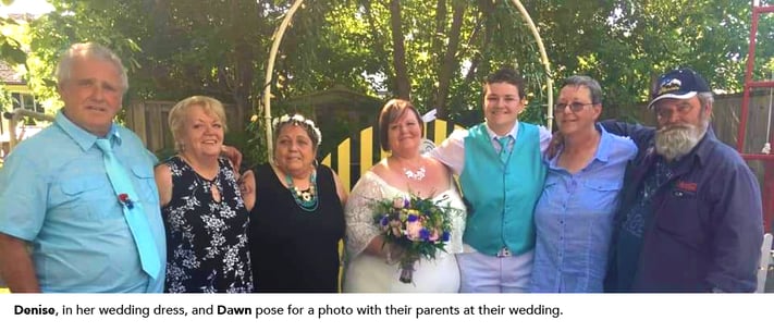 Denise, in her wedding dress, and Dawn pose for a photo with their parents at their wedding.