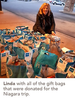 Photo of Linda with all of the gift bags that were donated for the Niagara trip.