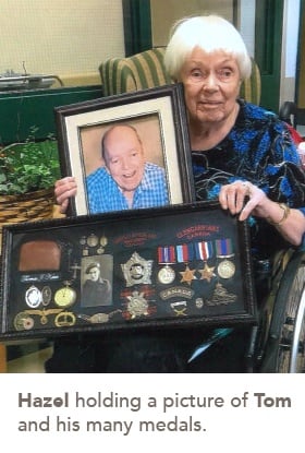 picture of Hazel holding a picture of Tom and his many medals.